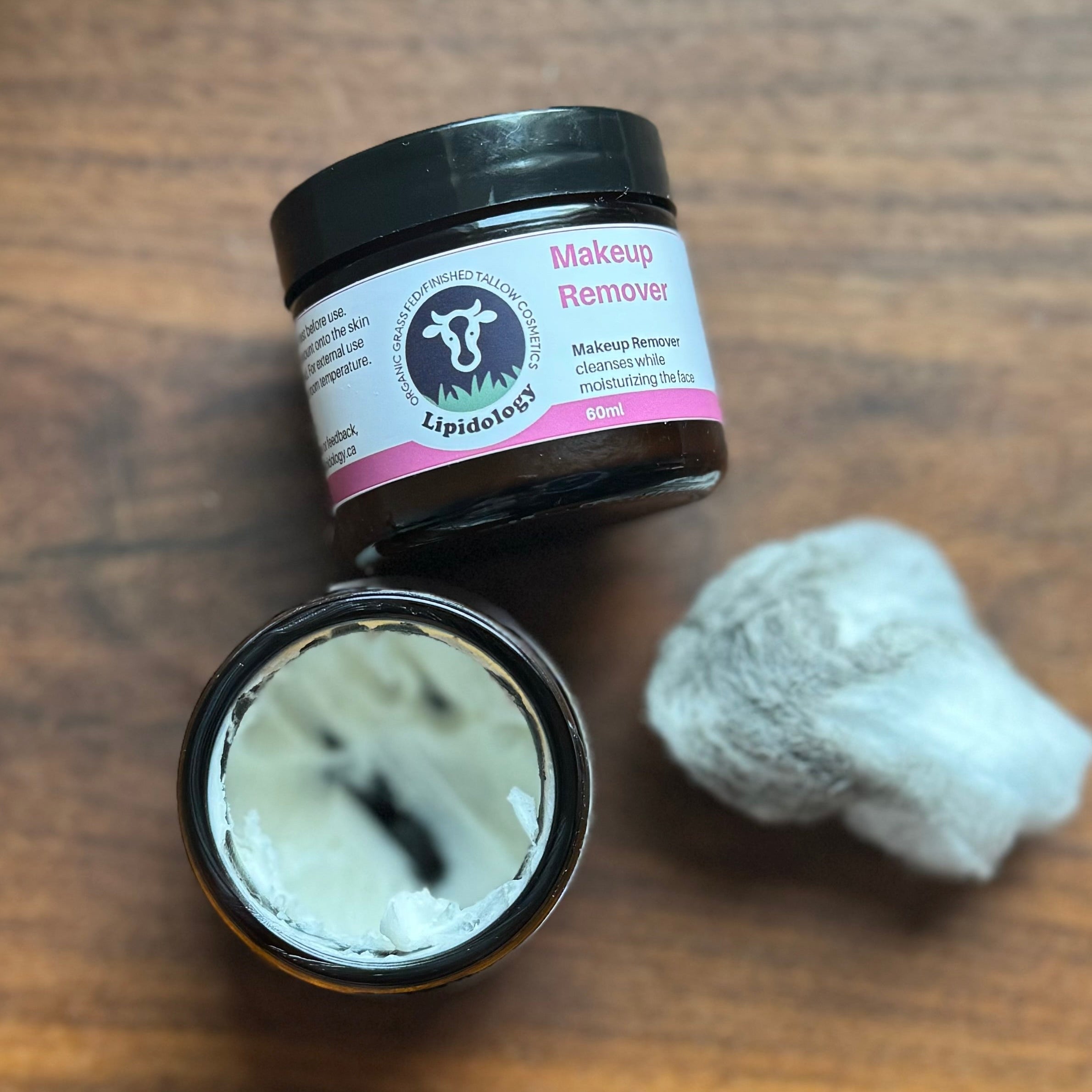 Makeup remover jar with a cotton pad on a wooden surface