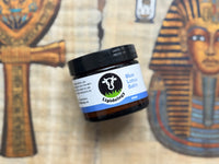 Jar of Lipidology Blue Lotus Balm with Egyptian-themed decor in the background